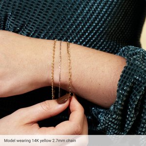 Model wearing a 2.7 mm curb and paperclip chain bracelet in 14K yellow gold